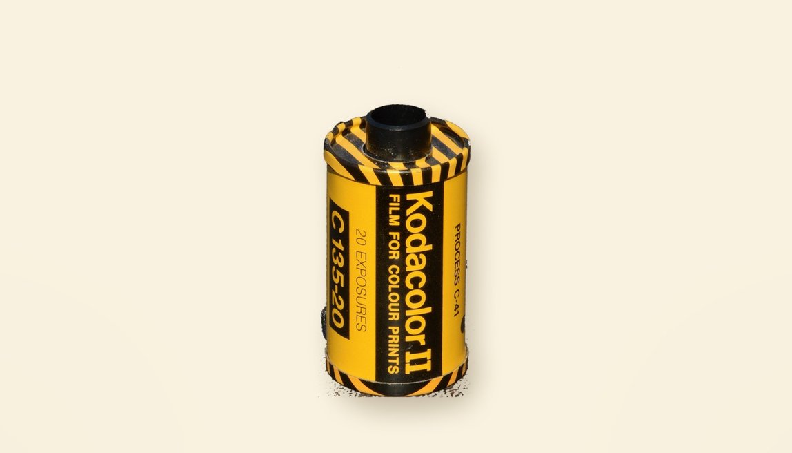 A Kodacolor II 35mm film cassette from the 1970s, yellow with black stripes