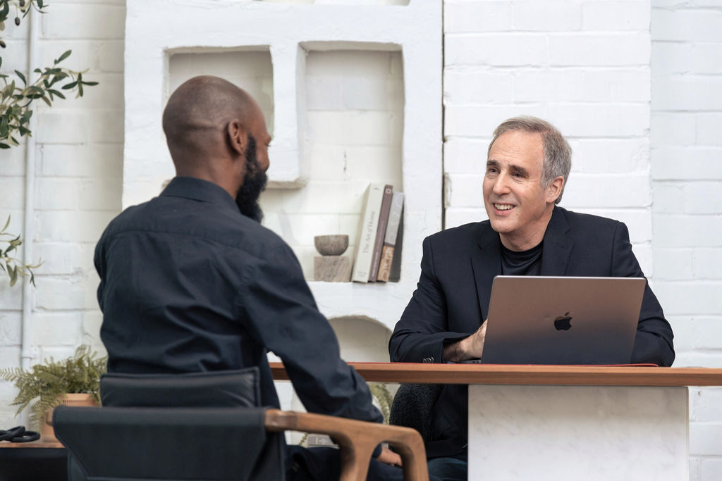 Mike Wittenstein across a table from a client in a one-on-one coaching conversation, listening