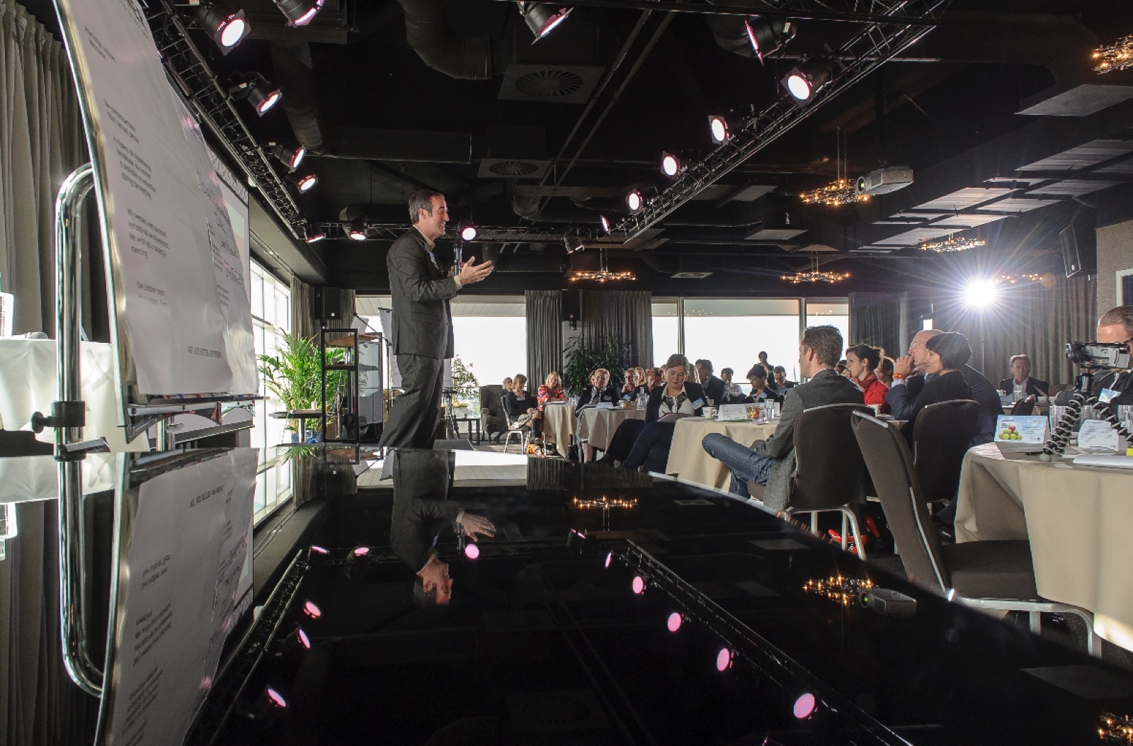 Mike Wittenstein leading a working session in a conference room, seen reflected in a grand piano, with the group listening