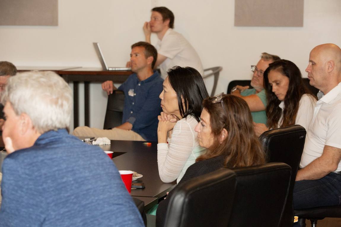 A row of attendees leaning in, listening closely.